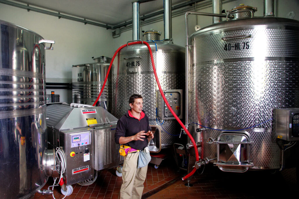 man standing in front of 4 very large stainless steel wine tanks