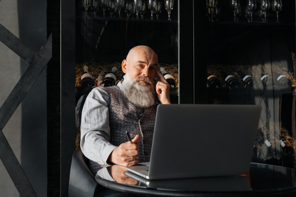 a man sitting in front of his laptop computer on his cell phone