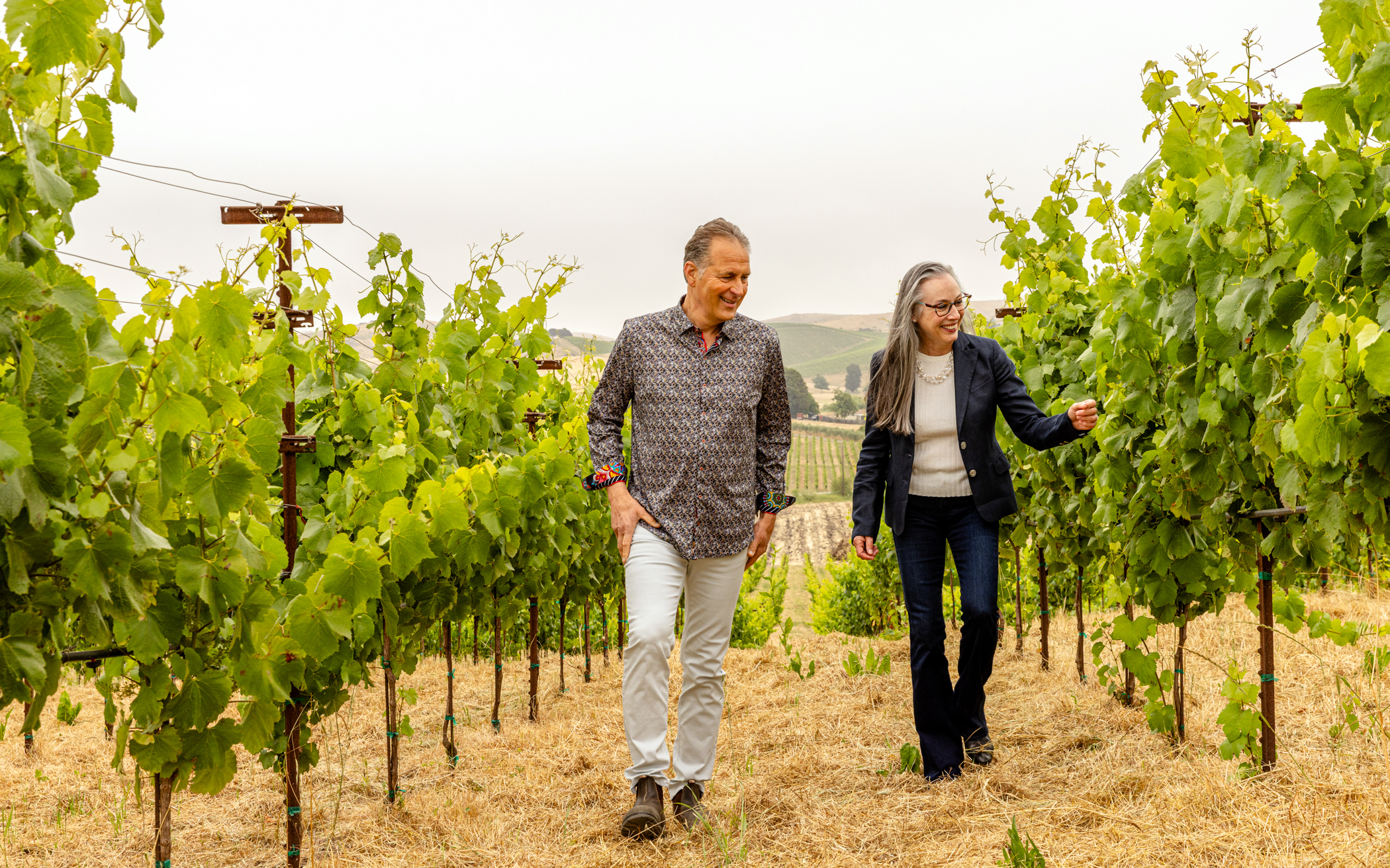 Mike Grgich walking with a woman in the grape vineyard