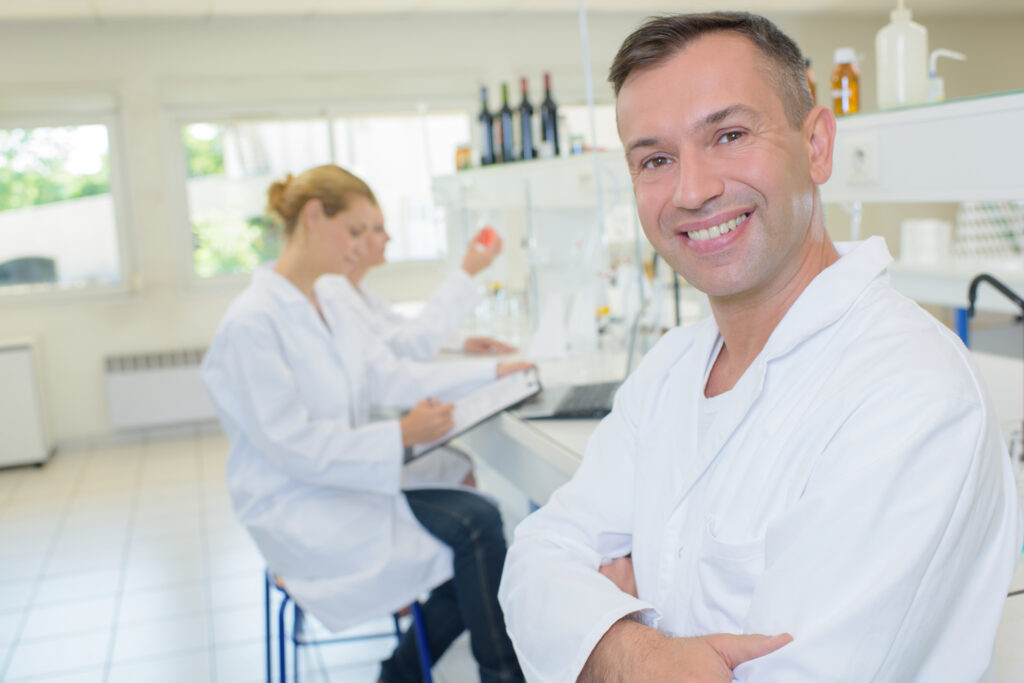 a man and 2 women in lab coats working in a lab
